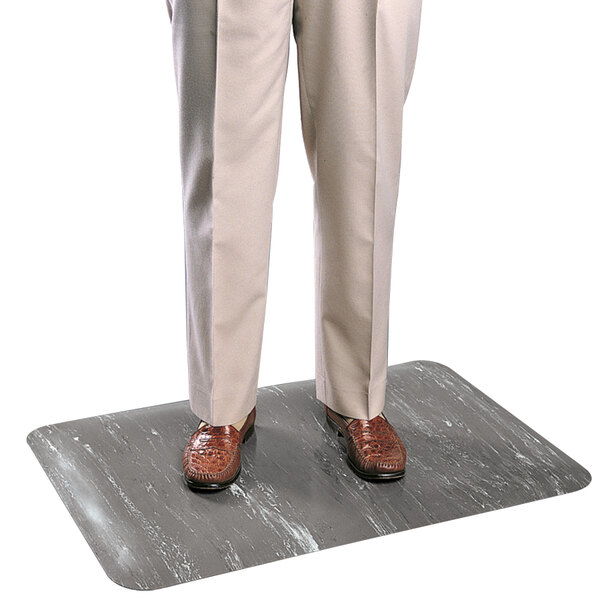 A person standing on a marbled dark gray rubber anti-fatigue mat.