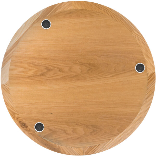A BFM Seating round natural wood table top with wireless chargers.