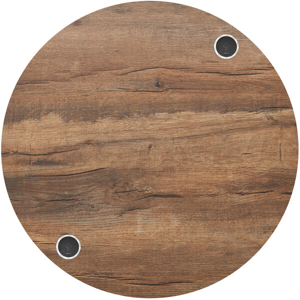 A BFM Seating Relic round knotty pine table top with two wireless chargers.