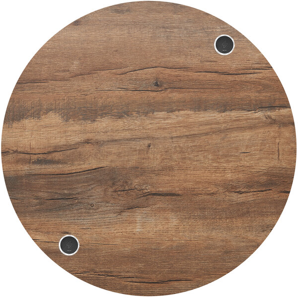 A BFM Seating Relic round knotty pine table top with wireless chargers and holes in it.