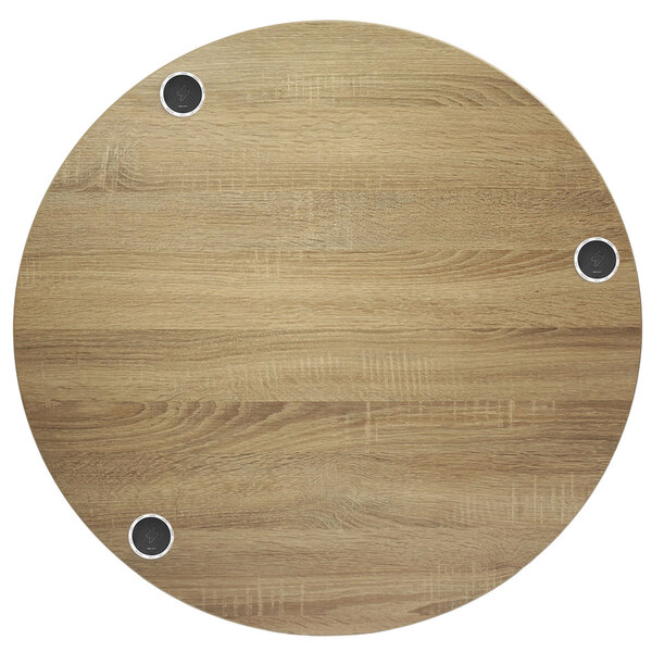 A BFM Seating round wood tabletop with metal wireless chargers.