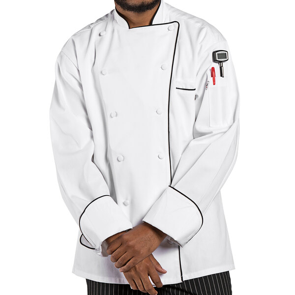 A man wearing a white Uncommon Chef long sleeve chef coat with black piping.