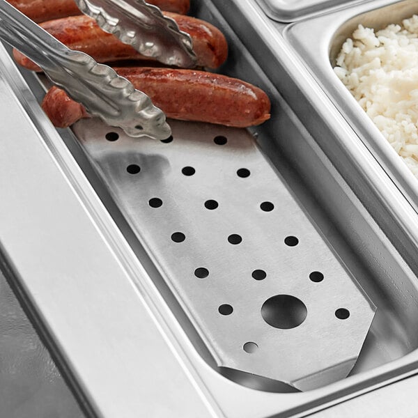 A close-up of a stainless steel false bottom in a tray of hot dogs.