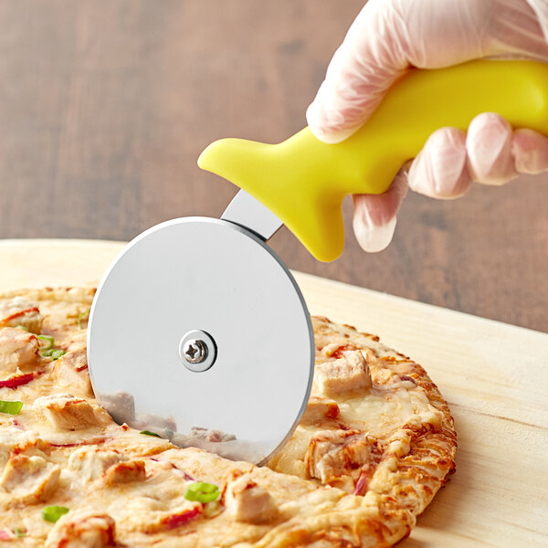 A person using a Choice 4" yellow-handled pizza cutter to cut a pizza.