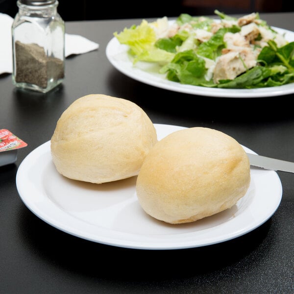 A white Thunder Group Nustone melamine plate with rolls and salad on it.