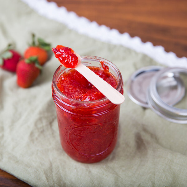 A jar of strawberry jam with a Eco-gecko wooden taster spoon inside.