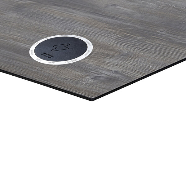 A close up of a rectangular driftwood composite laminate table top with 2 black wireless chargers.