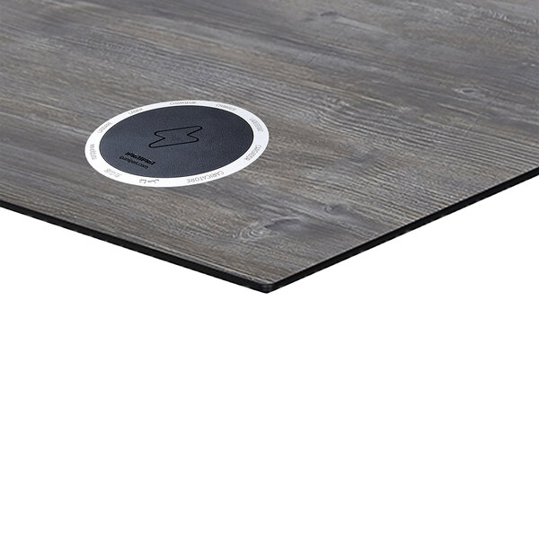 A BFM Seating rectangular driftwood table top with a black circle for wireless charging.