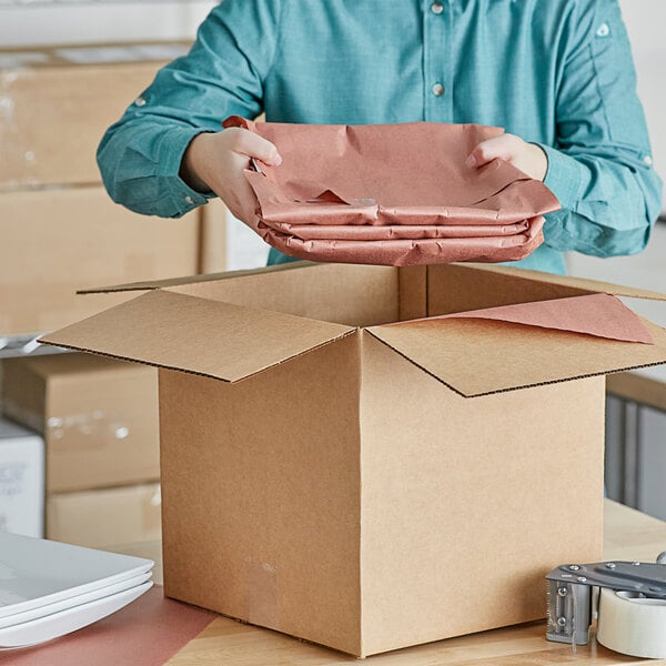 A man opening a box with a stack of Lavex pink void fill paper.