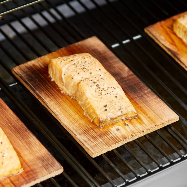 A piece of cooked salmon on a Backyard Pro cedar wood grilling plank.