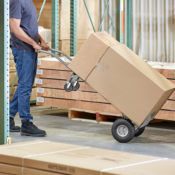 A man using a Lavex 2-in-1 hand truck to move a large box.