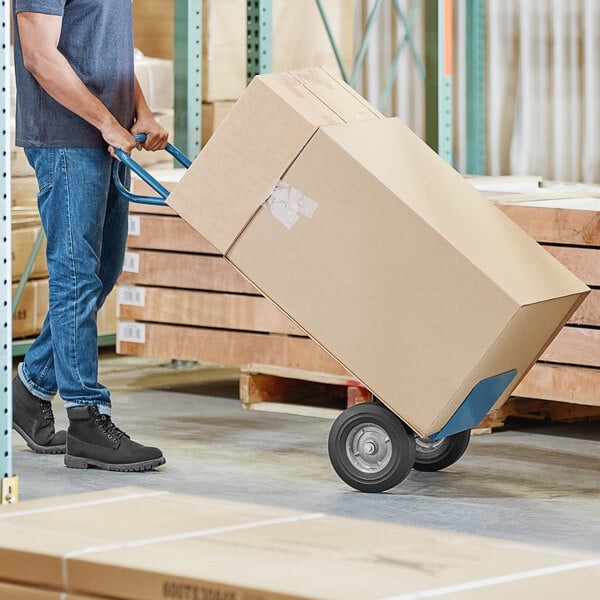 A person pushing a Lavex hand truck with a large box.