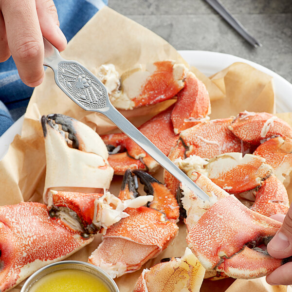 A person using a Choice stainless steel shellfish fork to eat a crab claw.
