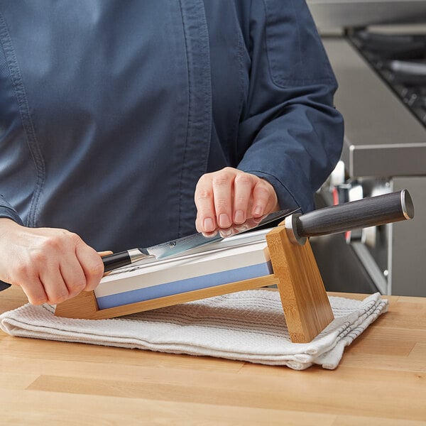 A person using a Shun knife to sharpen a metal object.
