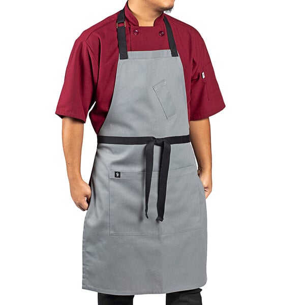 A man wearing a Uncommon Chef gray poly-cotton apron with black webbing and 3 pockets.