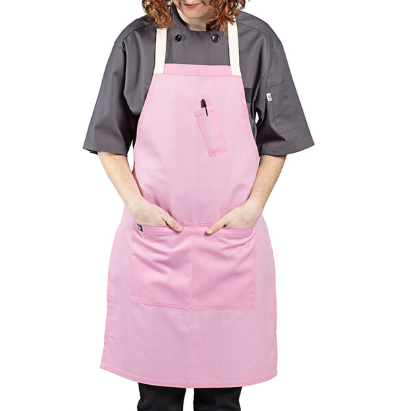 A woman wearing a pink Uncommon Chef bib apron.