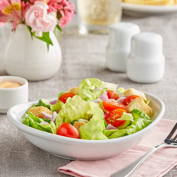 A Tuxton white porcelain china bowl filled with salad, tomatoes, and lettuce.