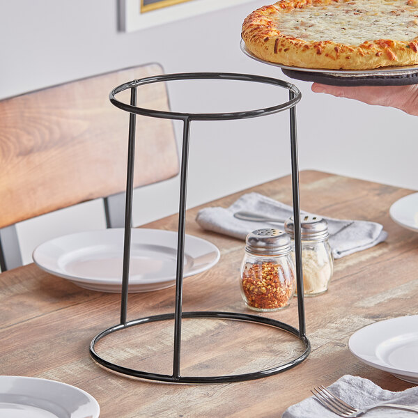 An American Metalcraft black rubberized pizza stand holding a pizza on a table.