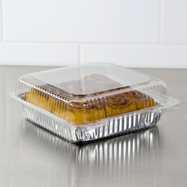 A Dart clear plastic oblong container with a cinnamon roll inside.