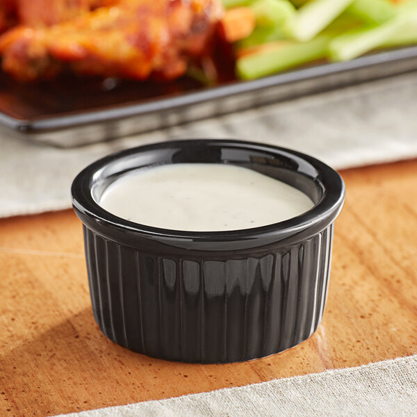 A black Acopa fluted stoneware ramekin filled with white sauce.