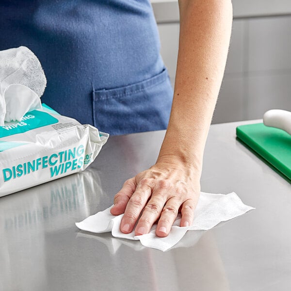 A woman using a WipesPlus disinfecting wipe to clean a surface.