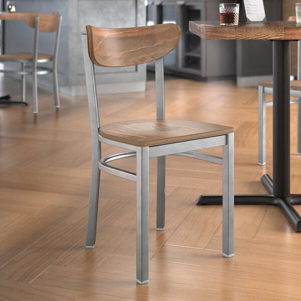 A Lancaster Table & Seating wooden chair with a clear coat finish on a table in a restaurant dining area.