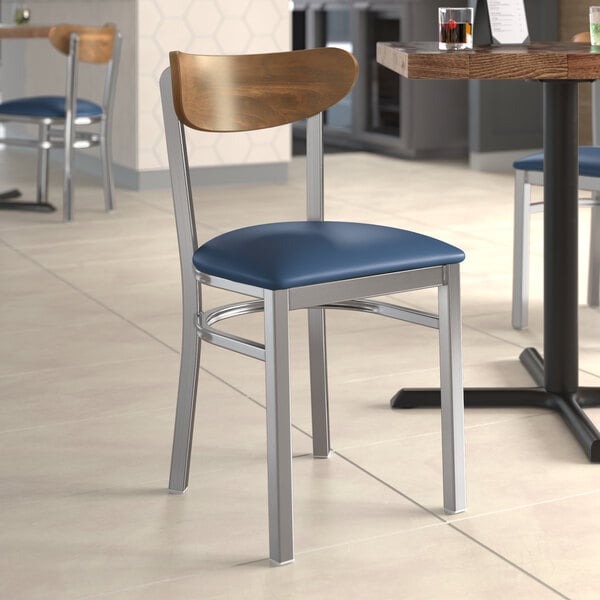 A Lancaster Table & Seating Boomerang chair with a navy vinyl seat at a restaurant table.