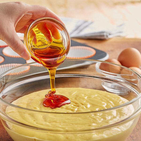A person pouring LorAnn Oils Liquid Soy Lecithin into a bowl of batter.