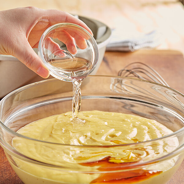 A hand pouring liquid into a bowl of food.