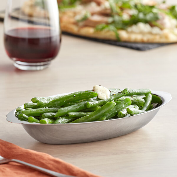 A Vollrath stainless steel oval au gratin dish filled with green beans on a table.