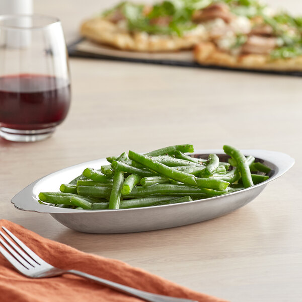 A Vollrath oval au gratin dish filled with green beans on a table.