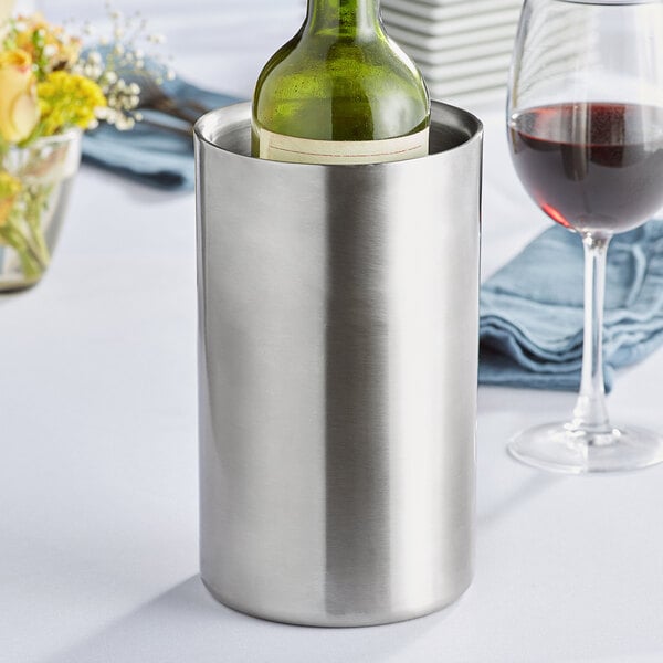 An Acopa double-walled stainless steel wine cooler holding a bottle of wine on a table.