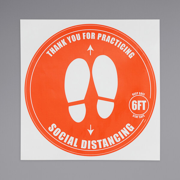 An orange American Metalcraft social distancing floor decal with white text and footprints.