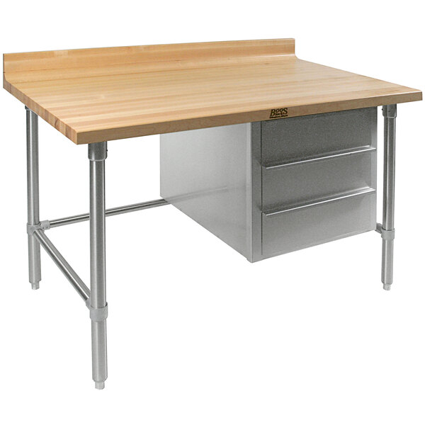A John Boos wood top work table with a stainless steel base and drawers.
