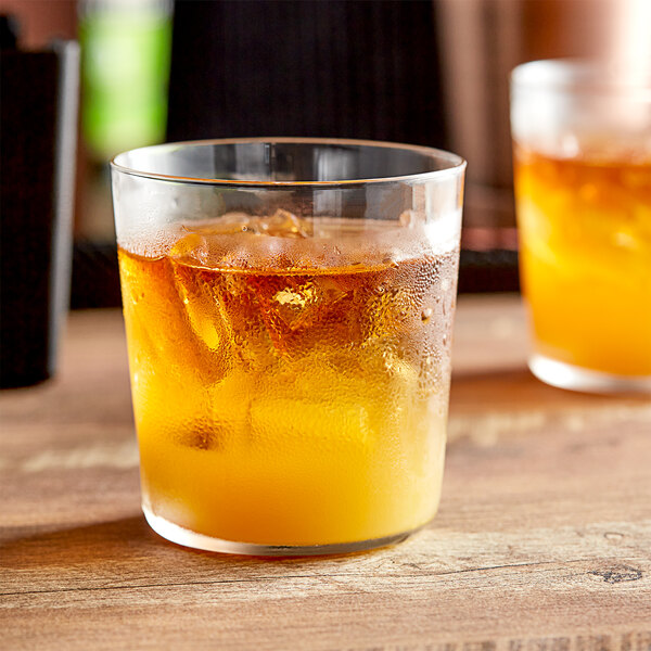 Two Libbey rocks glasses filled with orange drinks and ice on a wooden table.