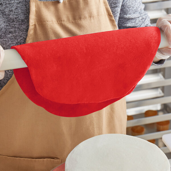 A person rolling red Satin Ice fondant with a red dough roller.