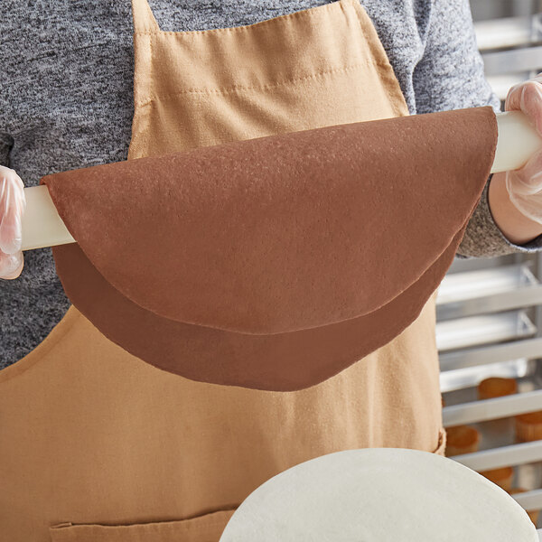 A person holding a roll of Satin Ice brown chocolate-flavored fondant.