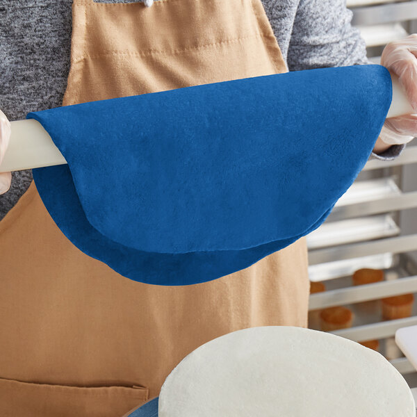 A person using Satin Ice Riptide Blue chocolate-flavored fondant to cover a cake.