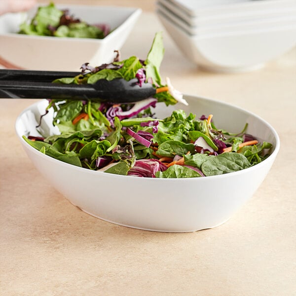 A Tablecraft white melamine oval bowl filled with salad.