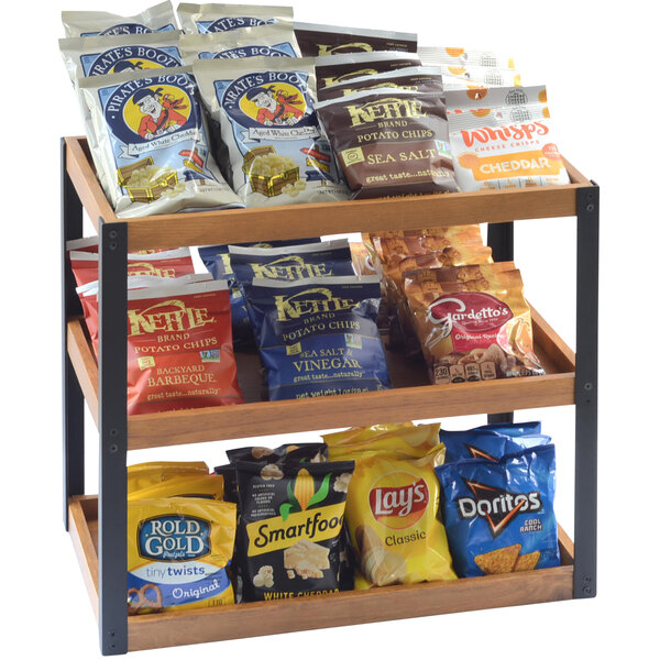 A Cal-Mil wood merchandiser with snacks including chips and popcorn on it.