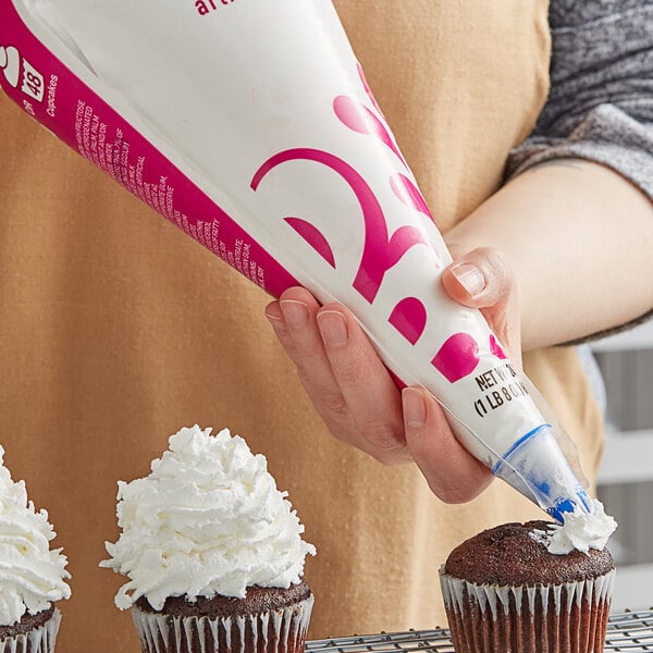 A person using Rich's Bettercreme vanilla whipped icing in a pastry bag to frost a cupcake.