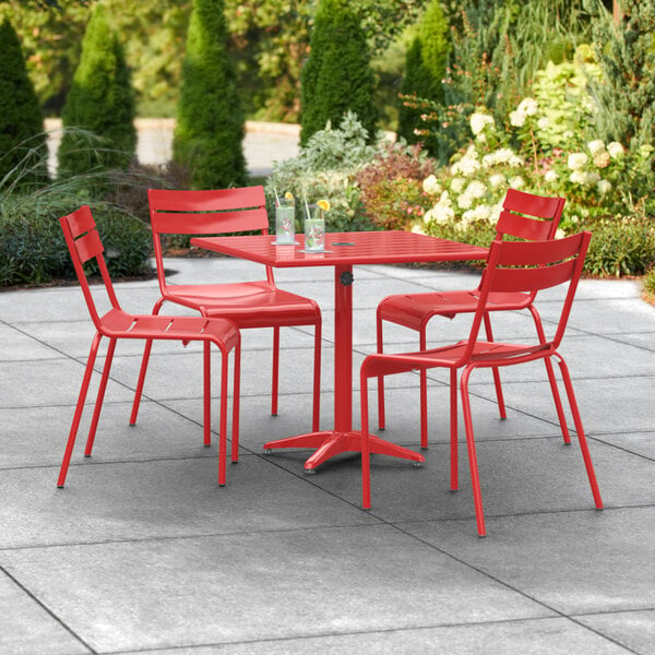 A red Lancaster Table & Seating outdoor dining table with chairs on a patio.
