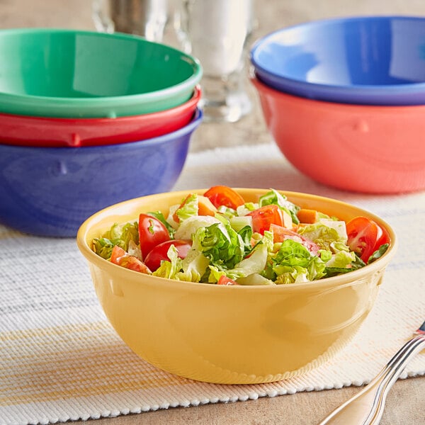 A close-up of a green Acopa Foundations melamine bowl filled with salad on a table.
