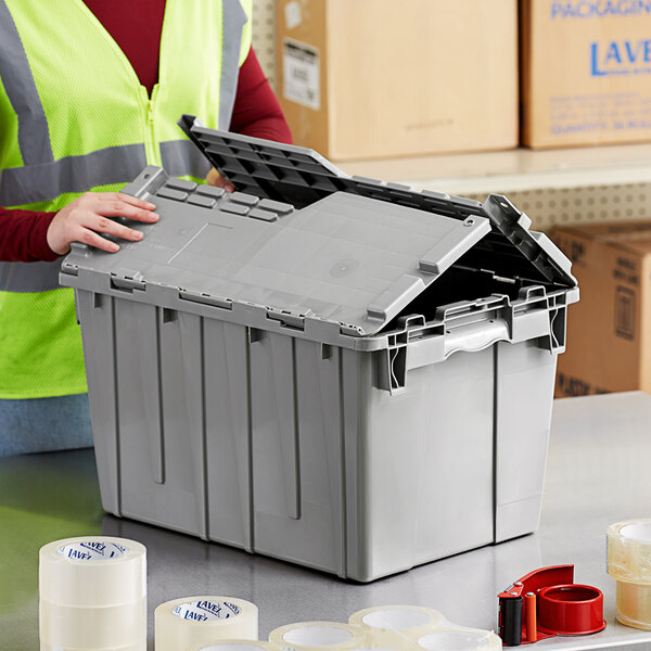 A person in a safety vest opening a Lavex gray plastic industrial tote.