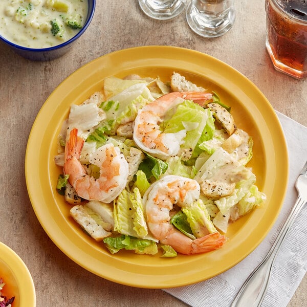A plate of shrimp caesar salad on a yellow Acopa Foundations melamine plate.