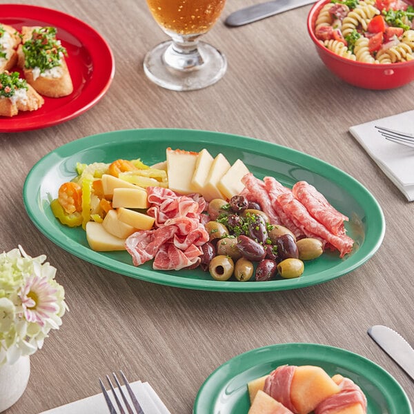 An oval green melamine platter on a table with food.