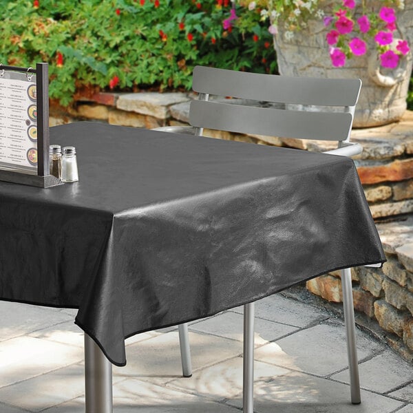 A black table with a Choice black vinyl table cover on a patio.