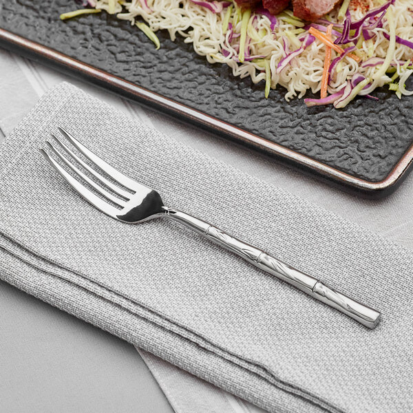 An Acopa stainless steel dinner fork on a plate of noodles and vegetables.