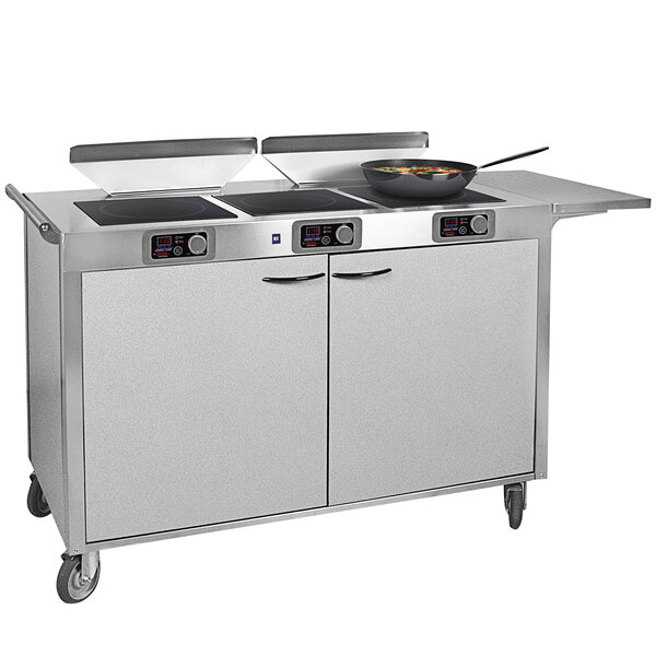 A large stainless steel Spring USA mobile induction cooking cart with pans on top.