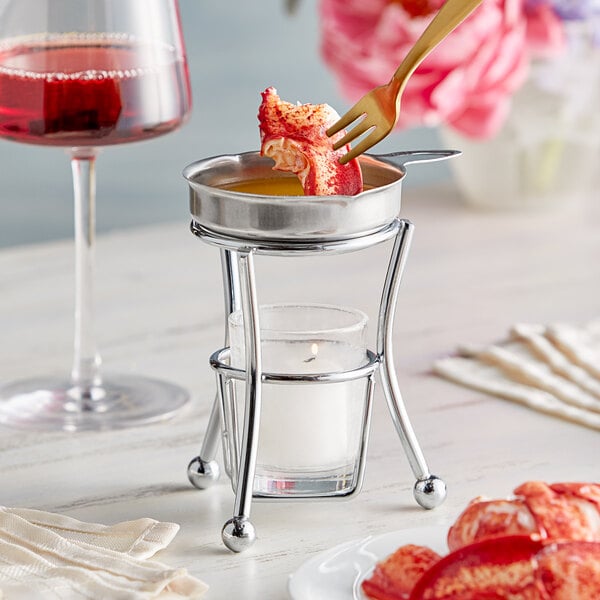 A candle in a glass holder on a Vollrath butter melter.